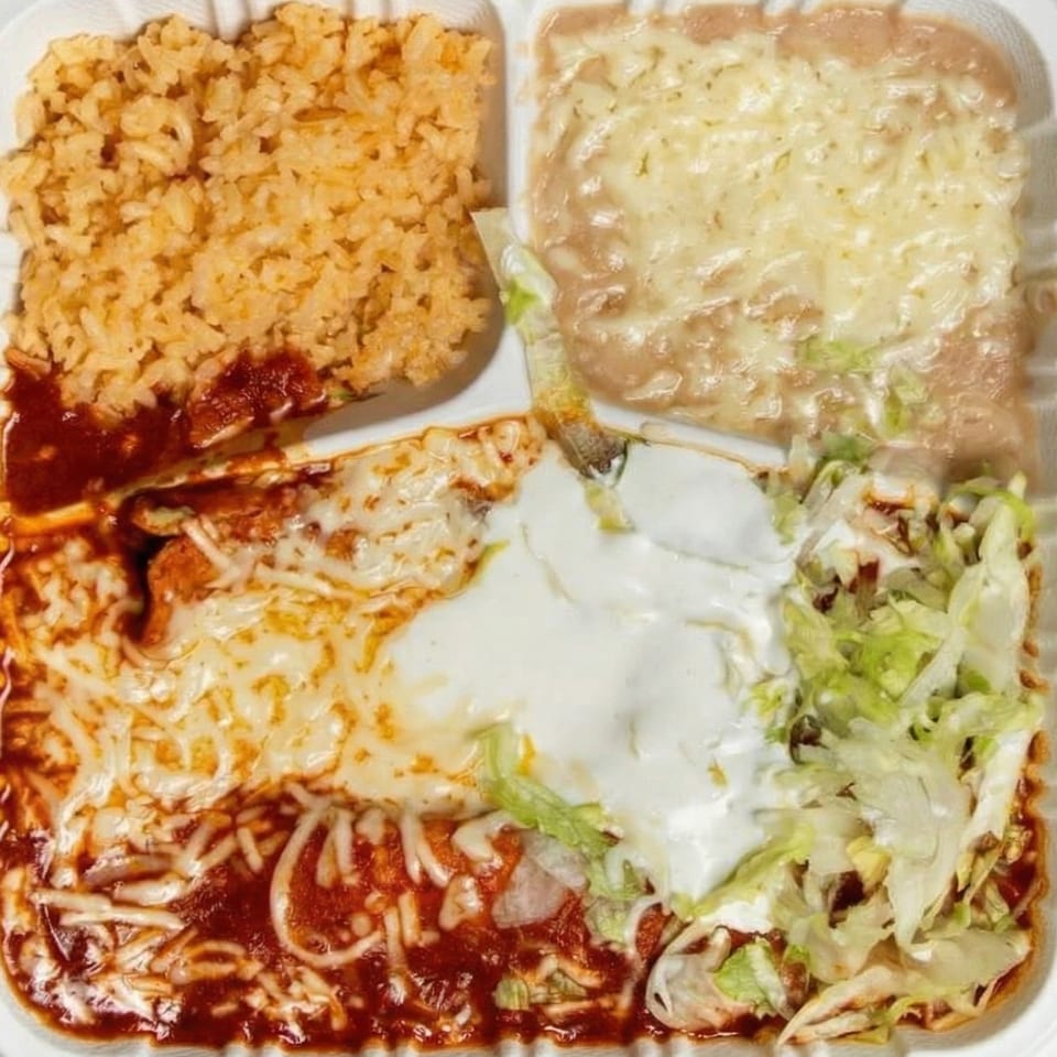 A Mexican combination plate with rice, refried beans, enchiladas, sour cream, and lettuce.